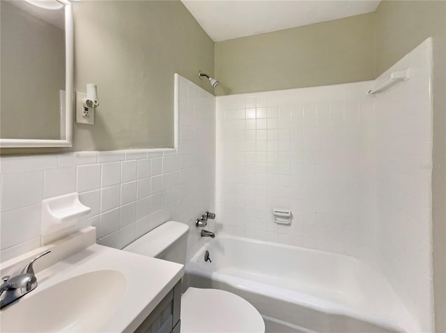 full bathroom with tiled shower / bath combo, toilet, tile walls, and vanity