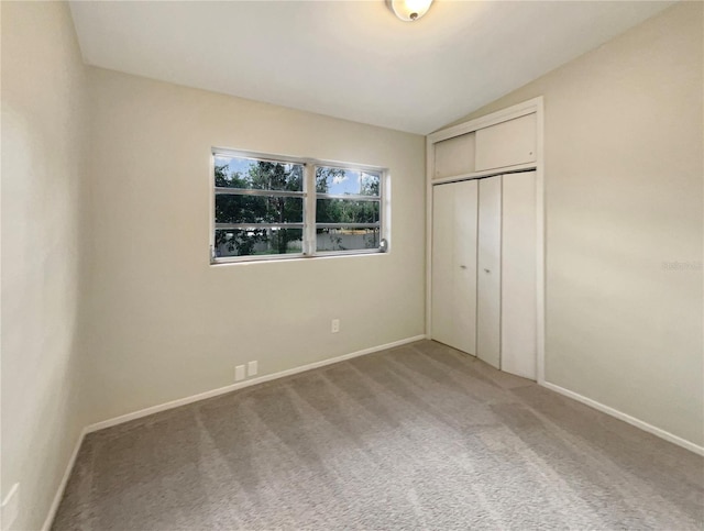 unfurnished bedroom featuring carpet floors, vaulted ceiling, and a closet