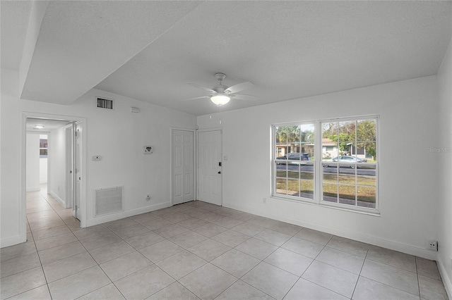 empty room with ceiling fan, a textured ceiling, and light tile patterned flooring