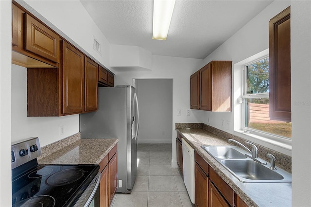 kitchen featuring appliances with stainless steel finishes, sink, light tile patterned floors, and a textured ceiling