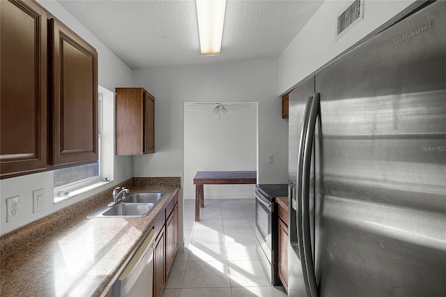 kitchen featuring appliances with stainless steel finishes, sink, a textured ceiling, and light tile patterned floors