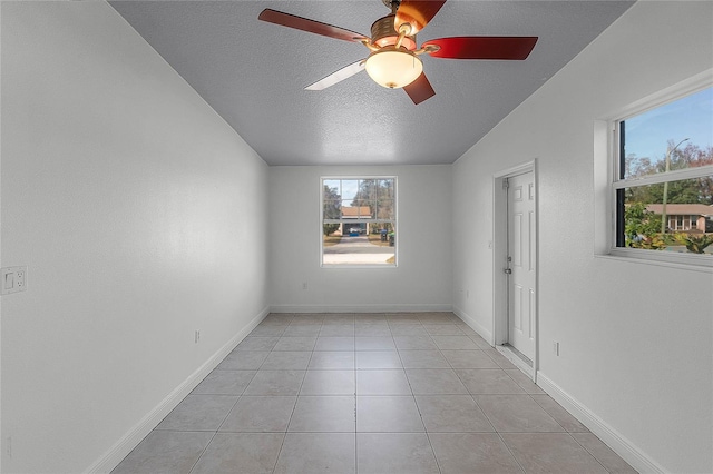 tiled empty room featuring ceiling fan and a textured ceiling