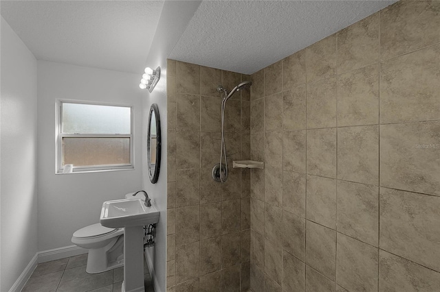 bathroom with tile patterned flooring, a textured ceiling, toilet, and tiled shower