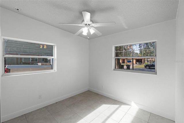 tiled spare room with a textured ceiling and ceiling fan