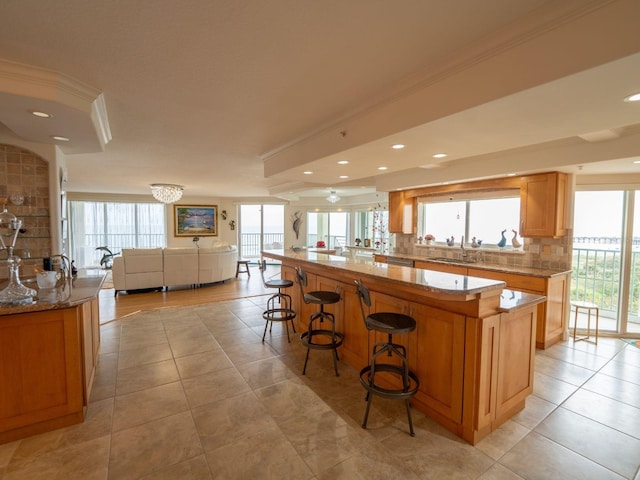 kitchen featuring sink, crown molding, decorative backsplash, a breakfast bar, and a kitchen island