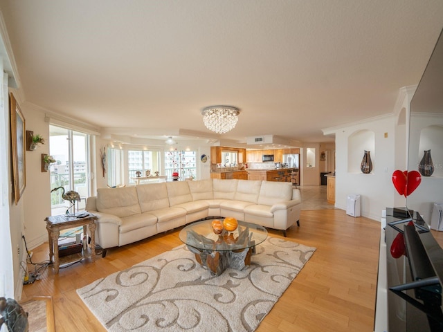 living room with a chandelier, ornamental molding, and light wood-type flooring