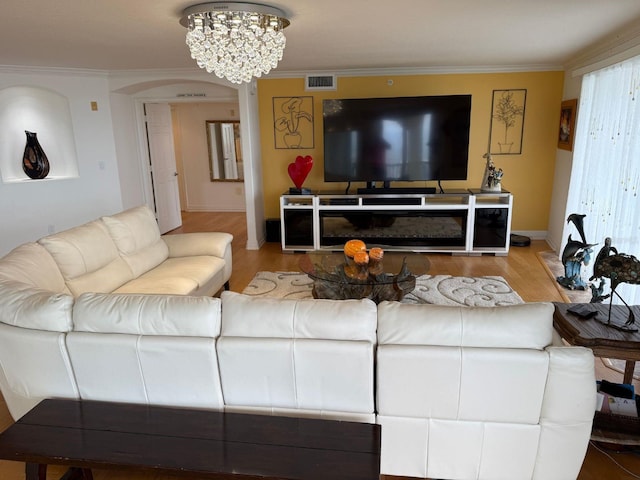 living room with hardwood / wood-style floors, a notable chandelier, and ornamental molding