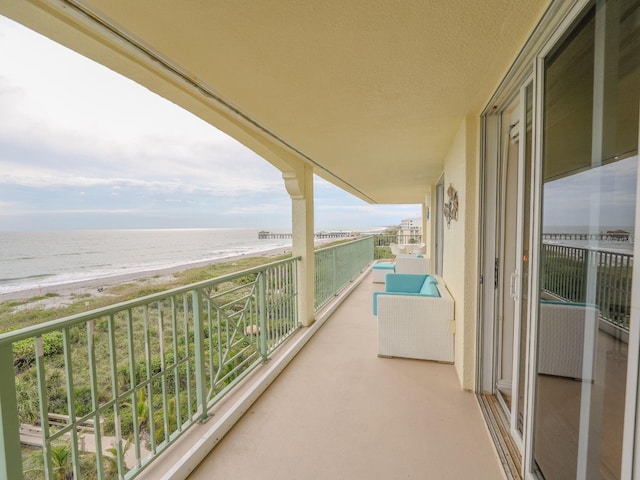 balcony with a water view and a view of the beach