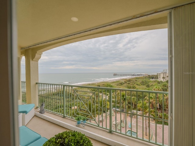 balcony with a water view and a view of the beach