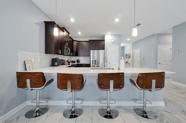 kitchen with sink, stainless steel appliances, a kitchen breakfast bar, kitchen peninsula, and pendant lighting