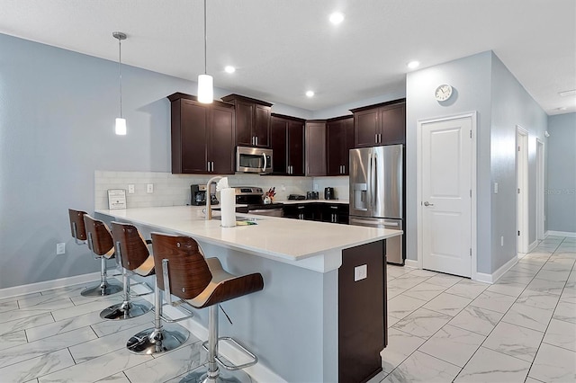 kitchen featuring a breakfast bar, sink, hanging light fixtures, appliances with stainless steel finishes, and kitchen peninsula