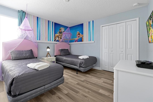 bedroom with a closet, a textured ceiling, and light wood-type flooring