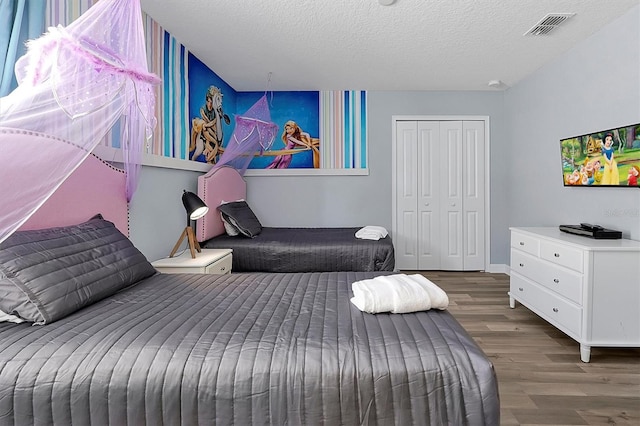 bedroom with a textured ceiling, a closet, and dark wood-type flooring