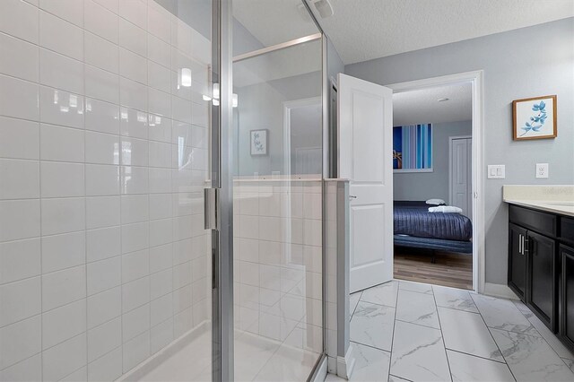 bathroom featuring vanity, an enclosed shower, a textured ceiling, and wood-type flooring