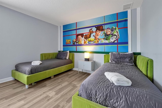 bedroom with light hardwood / wood-style floors and a textured ceiling