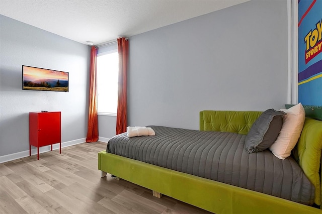 bedroom featuring a textured ceiling and light hardwood / wood-style flooring