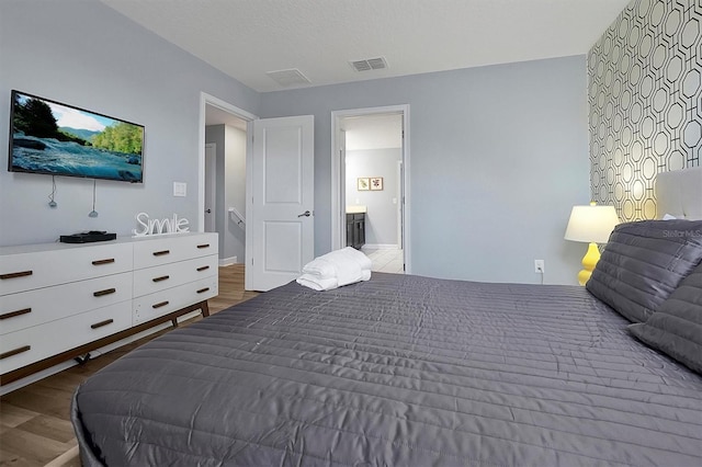 bedroom featuring connected bathroom and hardwood / wood-style flooring