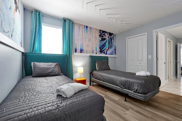 bedroom featuring light wood-type flooring, a textured ceiling, and a closet