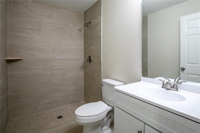 bathroom with tiled shower, a textured ceiling, vanity, and toilet