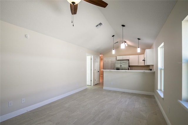 interior space featuring kitchen peninsula, hanging light fixtures, ceiling fan, stainless steel fridge, and white cabinetry