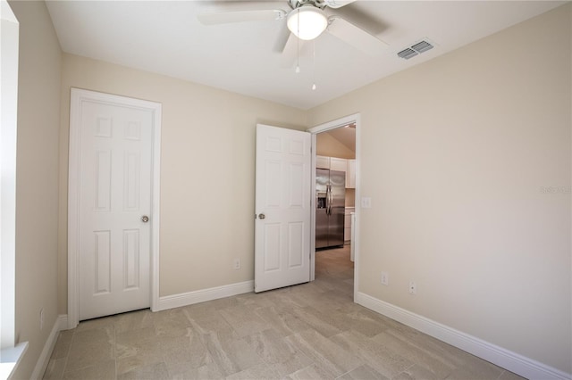 unfurnished bedroom with ceiling fan, light colored carpet, and stainless steel refrigerator with ice dispenser