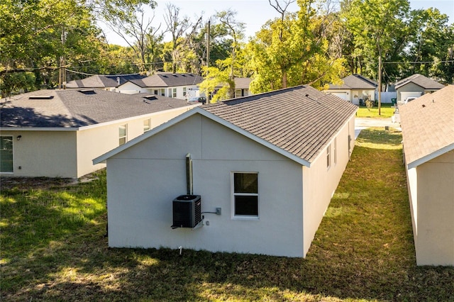 rear view of property with central air condition unit and a yard