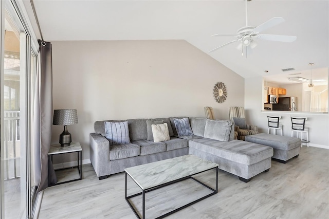 living room featuring ceiling fan, vaulted ceiling, and light wood-type flooring