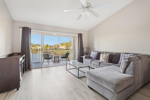 living room with ceiling fan, a water view, lofted ceiling, and light wood-type flooring