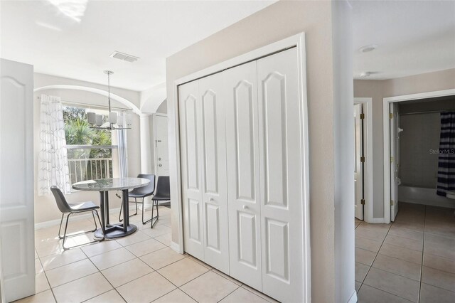 dining area with decorative columns, light tile patterned floors, and an inviting chandelier