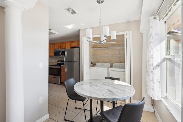 dining area featuring decorative columns, an inviting chandelier, light tile patterned floors, and washing machine and clothes dryer