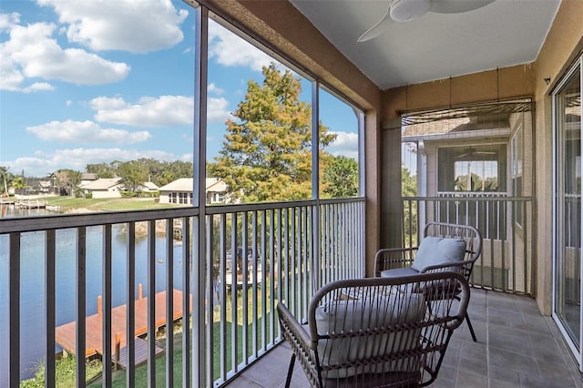 sunroom / solarium featuring ceiling fan and a water view