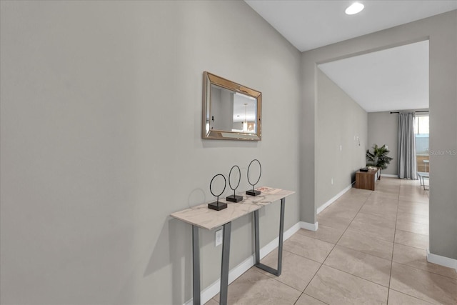 hall featuring baseboards and light tile patterned floors