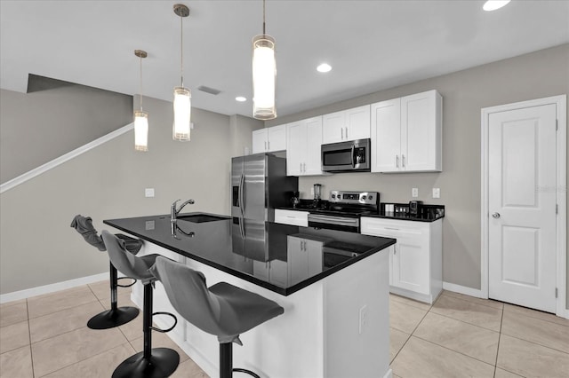 kitchen with stainless steel appliances, a sink, white cabinets, hanging light fixtures, and dark countertops