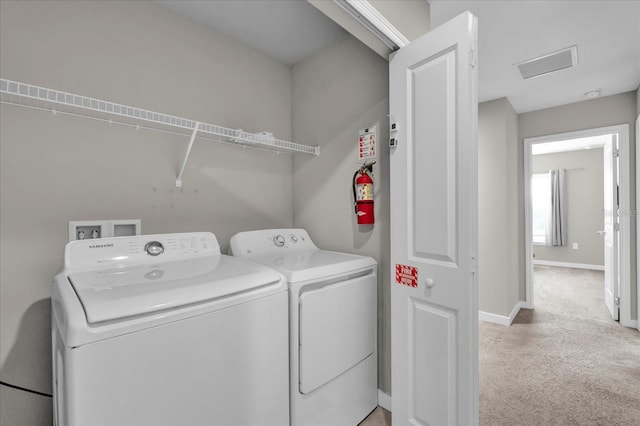 clothes washing area featuring baseboards, laundry area, washing machine and clothes dryer, and light colored carpet