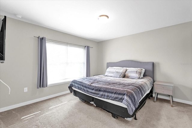 bedroom featuring light carpet and baseboards