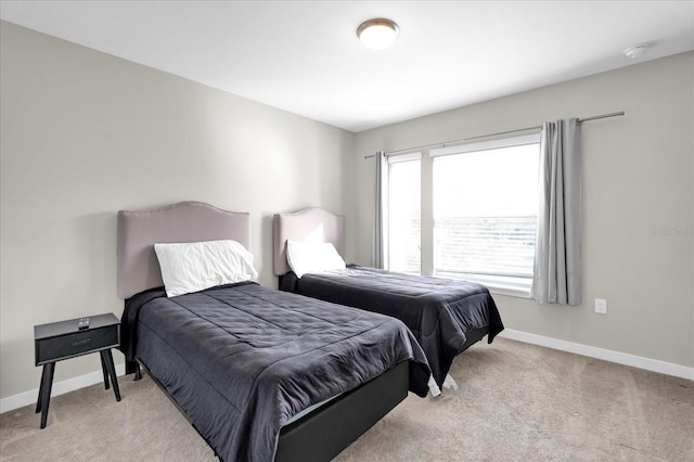 bedroom with baseboards and light colored carpet