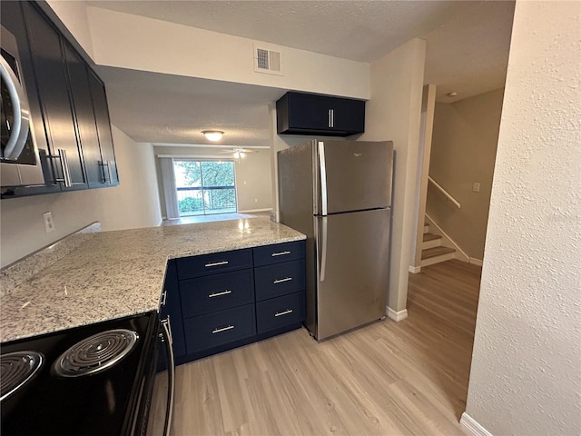 kitchen featuring stainless steel appliances, light stone counters, kitchen peninsula, light hardwood / wood-style floors, and a textured ceiling