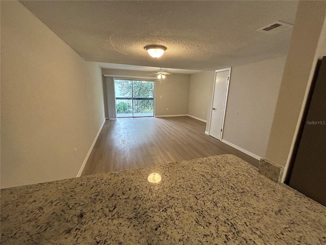 spare room featuring ceiling fan, wood-type flooring, and a textured ceiling