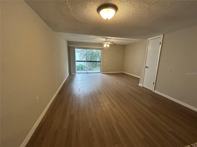 empty room with a textured ceiling, dark hardwood / wood-style floors, and ceiling fan