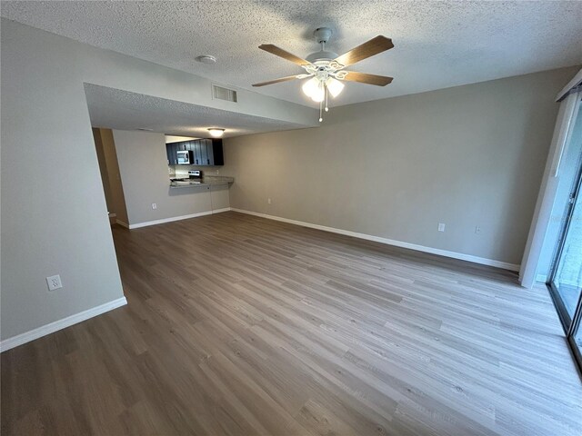 unfurnished living room featuring a textured ceiling, dark hardwood / wood-style floors, and ceiling fan