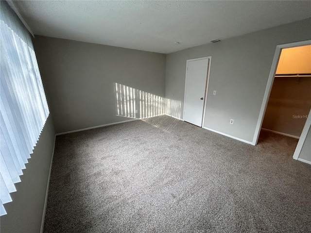 interior space with multiple windows, a walk in closet, carpet floors, and a closet