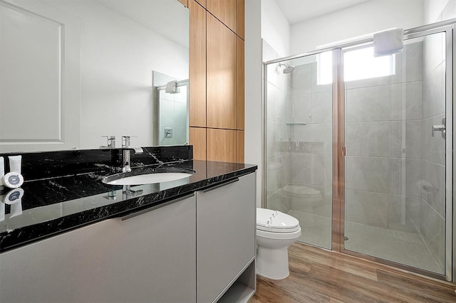 bathroom featuring hardwood / wood-style floors, vanity, toilet, and a shower with door