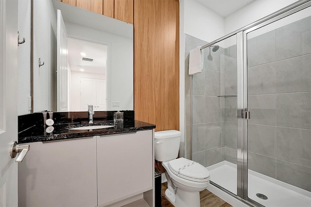 bathroom with wood-type flooring, vanity, toilet, and a shower with door