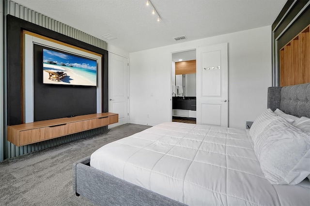 bedroom with track lighting, carpet, and a textured ceiling