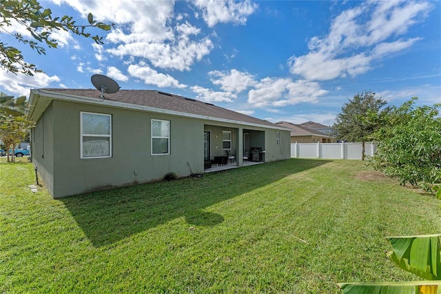 back of house featuring a lawn and a patio