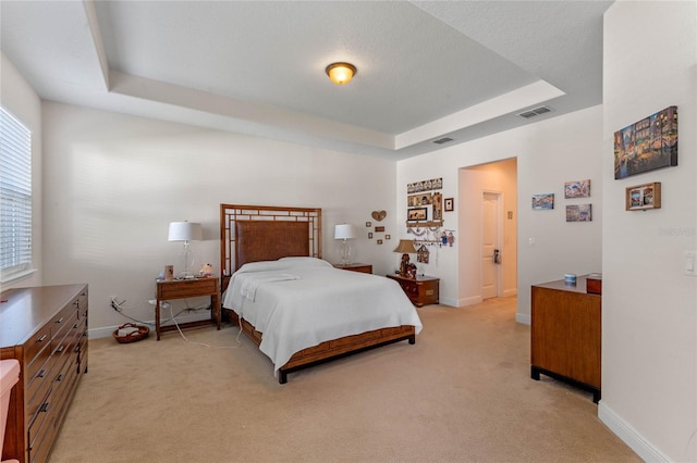 carpeted bedroom featuring a raised ceiling and a textured ceiling