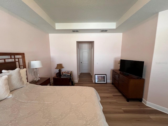 bedroom featuring a tray ceiling and wood-type flooring