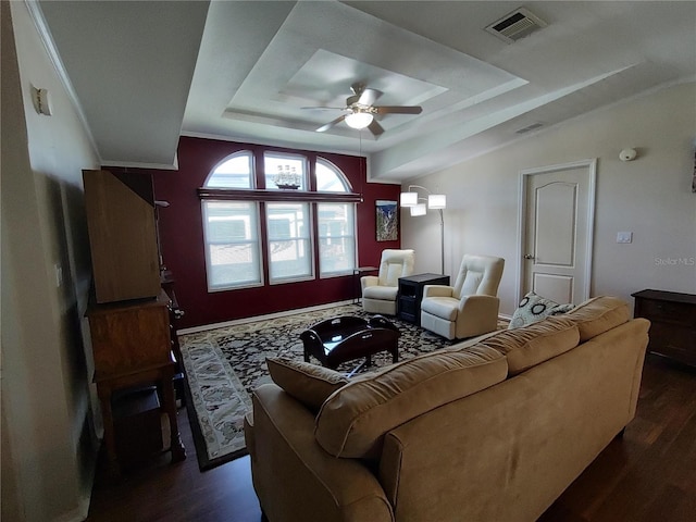 living room with ceiling fan, a raised ceiling, and dark hardwood / wood-style floors