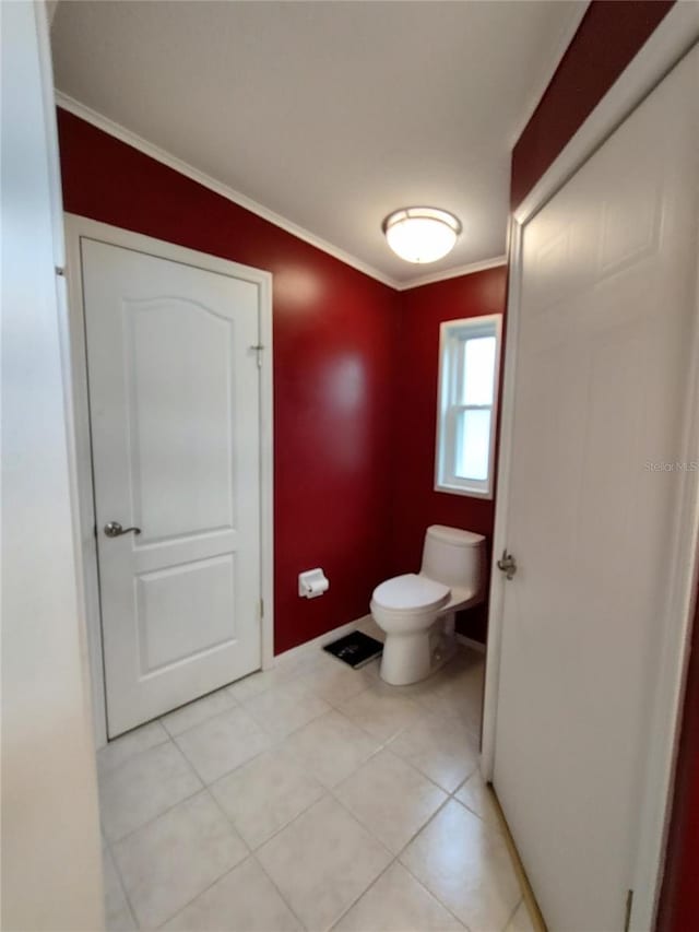 bathroom with toilet, ornamental molding, and tile patterned flooring