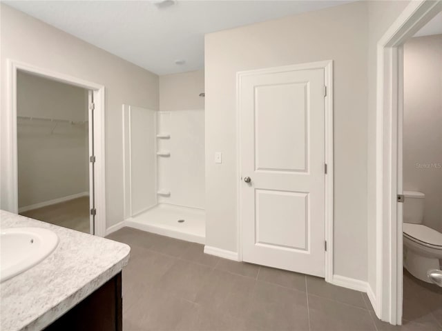 bathroom with tile patterned floors, walk in shower, vanity, and toilet